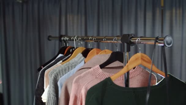 Nahaufnahme einer Frau nimmt einen rosafarbenen Pullover von einem Kleiderbügel mit Kleidung — Stockvideo
