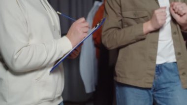 Kadının yakın çekimi, elbise dükkanındaki bir şeyi kağıda not eder.