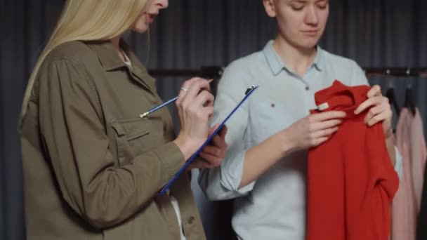 Close-up van vrouw maakt nota in papier van iets in kleding winkel — Stockvideo