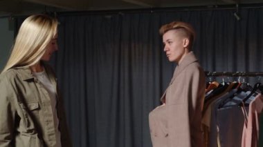 Genç bir kadın ikinci el giysi dükkanında pembe bir ceket deniyor.