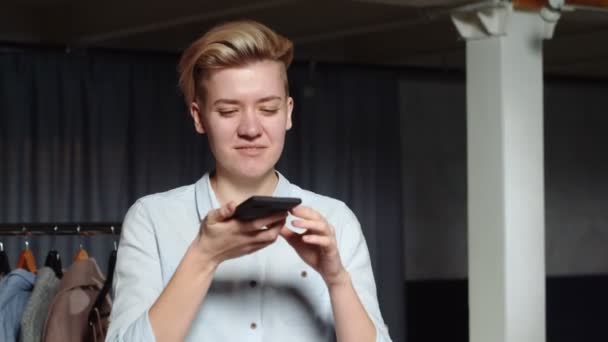 Junge Verkäuferin macht Handy-Foto in Second-Hand-Kleiderladen — Stockvideo