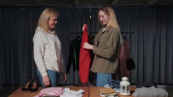 Jonge vrouwen Tweedehands winkelpersoneel sorteren kleding op tafel — Stockvideo