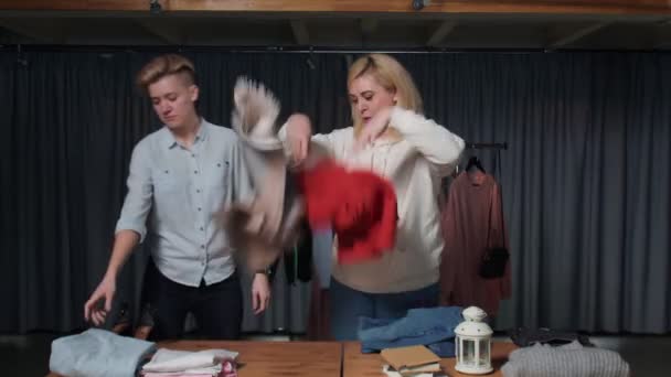 Młode kobiety Pracownicy sklepów z drugiej ręki sortują ubrania na stole — Wideo stockowe
