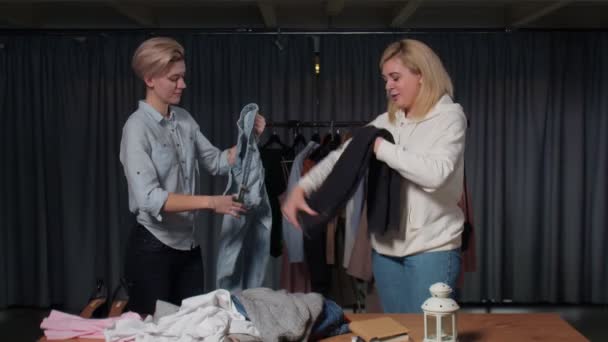 Jonge vrouwen Tweedehands winkelpersoneel sorteren kleding op tafel — Stockvideo