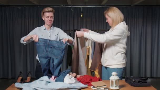 Jeunes femmes Travailleurs d'occasion trier les vêtements sur la table — Video