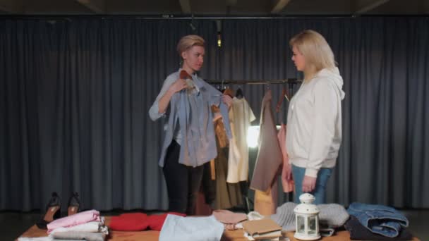 Женщина примеряет синюю рубашку в магазине подержанной одежды — стоковое видео