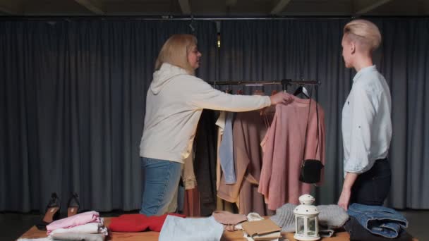 Giovane donna prova un maglione rosa in negozio di vestiti di seconda mano — Video Stock