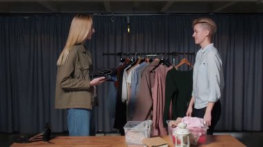 Bir kadın satıcının kapanışı ikinci el kıyafet dükkanında başka bir kadın müşteriye kıyafet verir.