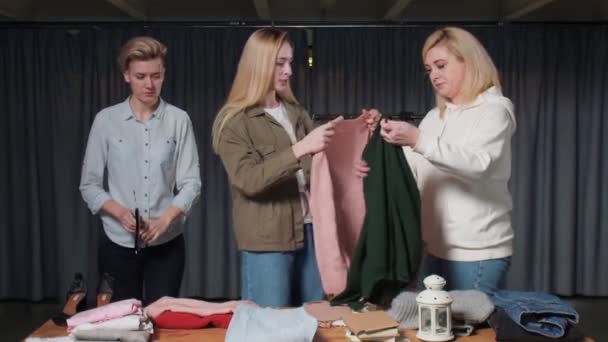 Jeunes femmes Travailleurs d'occasion trier les vêtements sur la table — Video