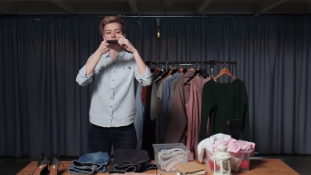Młoda sprzedawczyni robi zdjęcie ubrań na telefonie w sklepie z używanymi ubraniami — Wideo stockowe