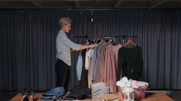 Młoda sprzedawczyni rozmawia przez telefon i pracuje w sklepie z używanymi ubraniami — Wideo stockowe