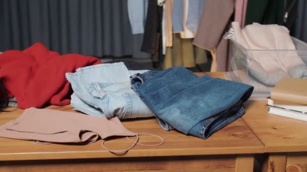 Mucha ropa estaba sobre la mesa en la tienda de segunda mano — Vídeo de stock