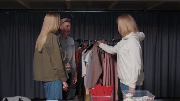 Jonge vrouw probeert een roze jas in tweedehands kleding winkel — Stockvideo