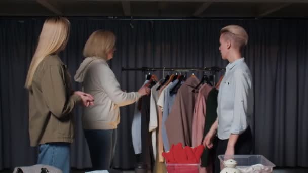 Blond vrouw probeert op een zwart blazer in tweedehands kleding winkel — Stockvideo