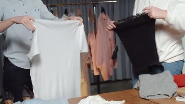 Nők közelsége Használt bolti munkások válogatják a ruhákat az asztalon — Stock videók