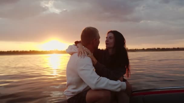 A guy and a girl cuddle cute at sunset sitting in a boat — Stock Video