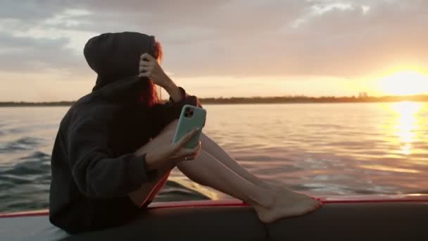 一个女人在日落时坐在汽艇上给自己照相 — 图库视频影像