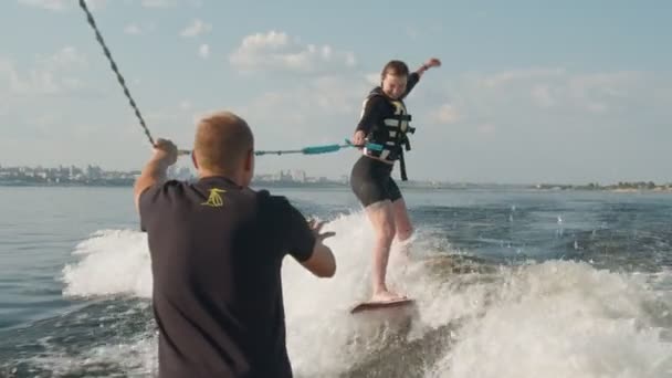 Dziewczyna jest surferką, jeździ na wakeboardzie. Doświadczony wakeboarder pomaga dziewczynie — Wideo stockowe