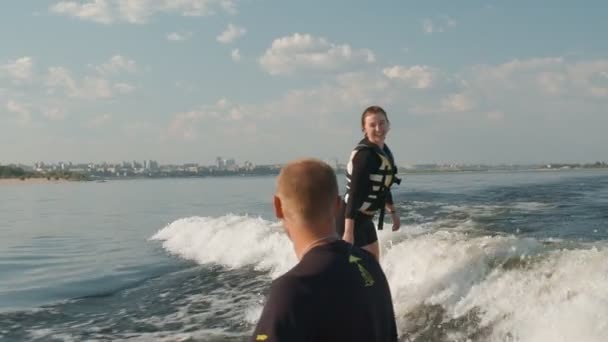 Dziewczyna jest surferką, jeździ na wakeboardzie. Doświadczony wakeboarder pomaga dziewczynie — Wideo stockowe