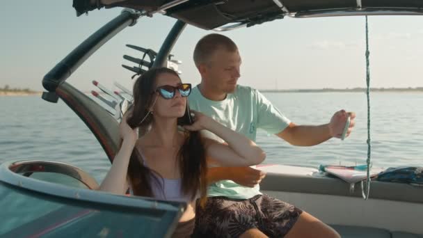 Een man en een vrouw zitten in een motorboot en nemen foto 's — Stockvideo