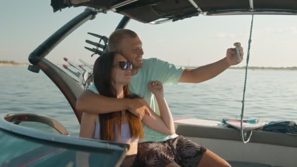 Um homem e uma mulher estão sentados em um barco a motor e tirando fotos — Vídeo de Stock