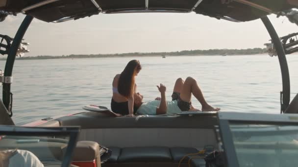 Um cara e uma menina estão sentados em um barco a motor, conversando e olhando para a distância. Ambiente romântico. — Vídeo de Stock