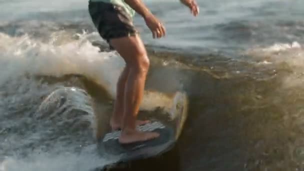 Een surfer springt op een wakeboard. Een ervaren wakeboarder spuit waterdruppels in de camera. — Stockvideo