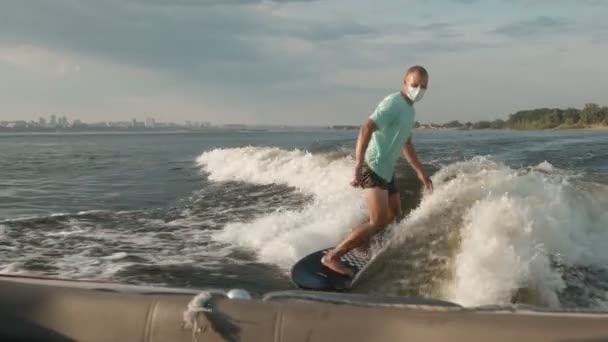 Surfer skaczący na desce w masce. Doświadczony wakeboarder chlapie krople wody do kamery. — Wideo stockowe