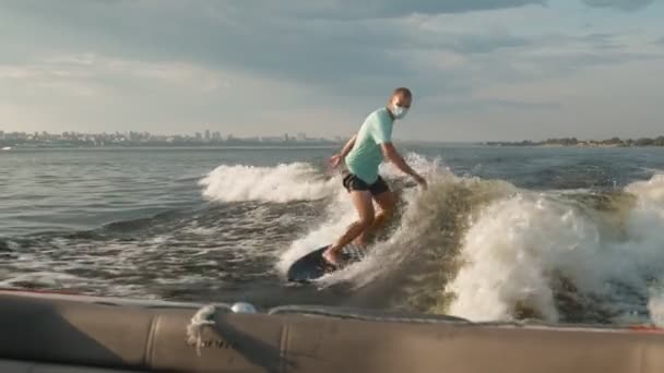 Surfař skákající na wakeboardu v masce. Zkušený wakeboardista cáká vodu kapky do kamery. — Stock video
