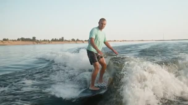 Ένας σέρφερ που πηδάει σε μια σανίδα. Ένας έμπειρος wakeboarder ψεκάζει νερό σταγόνες στην κάμερα. — Αρχείο Βίντεο