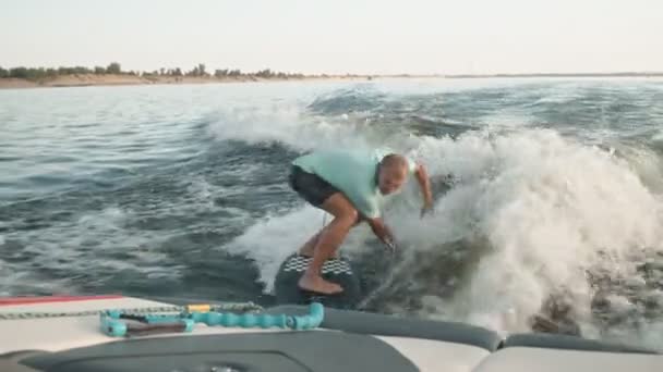 Een surfer springt op een wakeboard. Een ervaren wakeboarder spuit waterdruppels in de camera. — Stockvideo