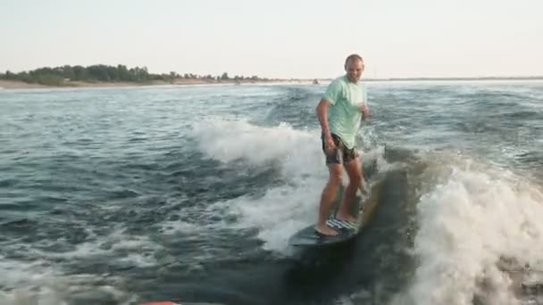 Peselancar melompat ke atas papan selancar. Sebuah wakeboarder berpengalaman menyemprotkan air tetes ke kamera. — Stok Video