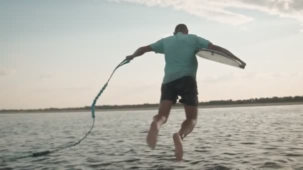 Un hombre con un wakeboard salta al agua — Vídeo de stock