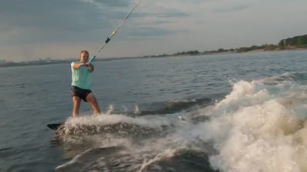 Ein Surfer springt auf einem Wakeboard. Ein erfahrener Wakeboarder sprüht Wassertropfen in die Kamera. — Stockvideo