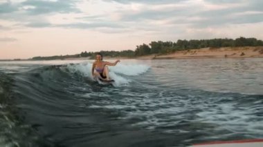 Wakeboard 'a atlayan dişi bir sörfçü. Deneyimli bir wakeboardcu kameraya su damlatıyor..