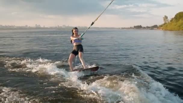 一个女冲浪者跳到了一块滑板上.一个有经验的觉醒者把水滴到相机里. — 图库视频影像
