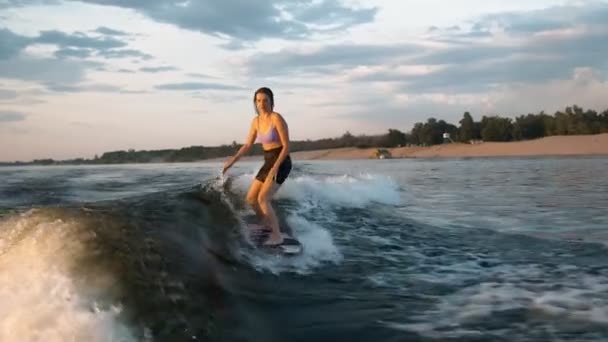 Surfařka skákající na wakeboardu. Zkušený wakeboardista cáká vodu kapky do kamery. — Stock video