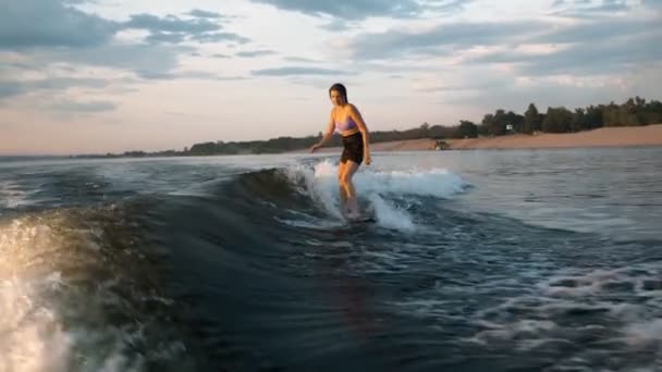 Samica surfera skacząca na desce. Doświadczony wakeboarder chlapie krople wody do kamery. — Wideo stockowe