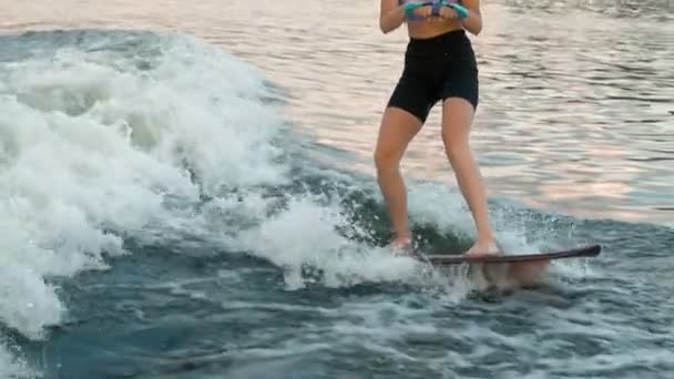 Μια γυναίκα σέρφερ που πηδάει σε μια σανίδα. Ένας έμπειρος wakeboarder ρίχνει νερό σταγόνες στην κάμερα. — Αρχείο Βίντεο