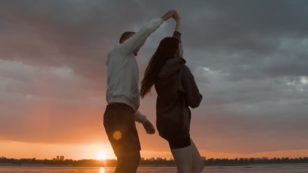 Un tipo rodea a una chica en una lancha motora contra el fondo de la puesta de sol. Ambiente romántico. — Vídeos de Stock