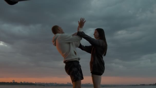 Um tipo e uma rapariga andam a brincar num barco a motor ao pôr-do-sol. Ambiente romântico. — Vídeo de Stock