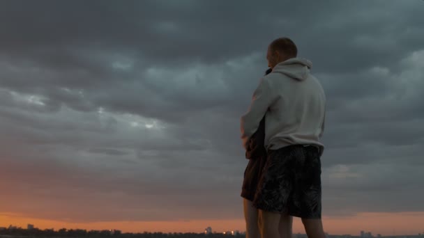 A guy and a girl are standing and cuddling sweetly in a motor boat and looking at the sunset. Romantic atmosphere. — Stock Video