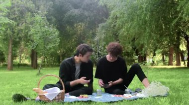 Yazın doğada telefona bakan iki genç.