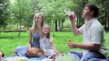 Yazın ailesiyle birlikte sabun köpüklerine izin veren bir adam.