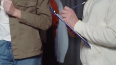 Kadının yakın çekimi, elbise dükkanındaki bir şeyi kağıda not eder.