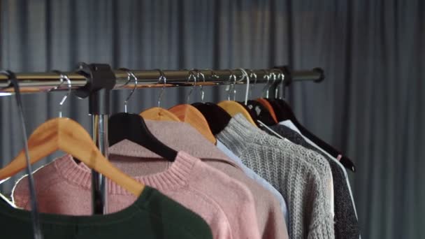 Nahaufnahme einer Frau nimmt einen grauen Pullover von einem Kleiderbügel mit Kleidung — Stockvideo