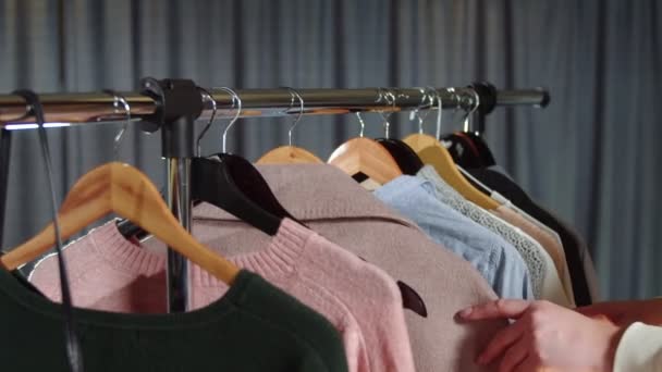 Κοντινό πλάνο της γυναίκας κοιτάζει τα ρούχα στην κρεμάστρα — Αρχείο Βίντεο