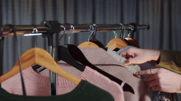 Close up de mulher olha para roupas no cabide — Vídeo de Stock