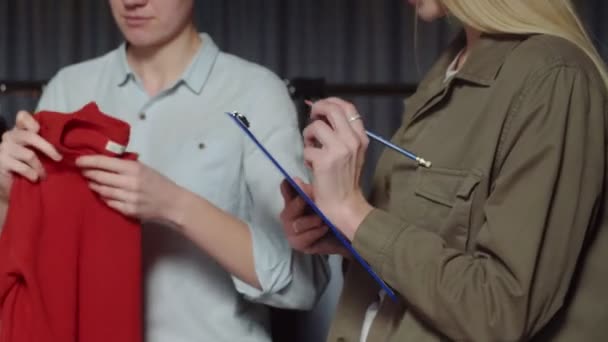 Blisko kobiety robi notatki na papierze o czymś w sklepie z ubraniami — Wideo stockowe