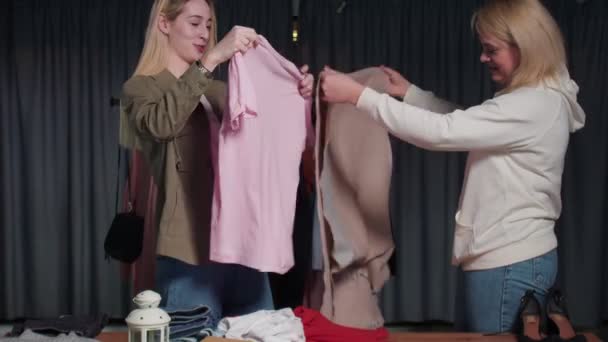 Junge Frauen aus dem Second-Hand-Laden sortieren Kleidung auf dem Tisch — Stockvideo